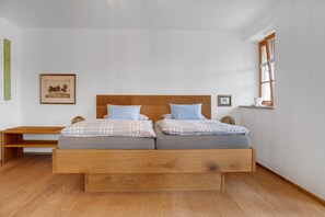 Une chambre à coucher avec un lit en bois, deux oreillers, une table de chevet, un tableau encadré au mur et une fenêtre.