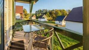 Un espacio al aire libre techado con una mesa y sillas, con vistas a una hilera de casas con tejados inclinados.