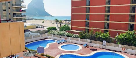 Ett hotell med ett poolområde som inkluderar flera pooler och solstolar.