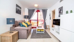 Ein modernes Wohnzimmer mit Sofa, Couchtisch, Fernseher und Küchenzeile.