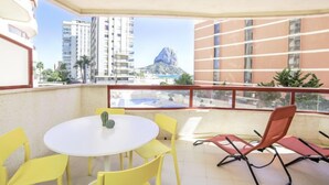 Ein Balkon mit gelben Stühlen, einem weißen Tisch und einem roten Sessel.