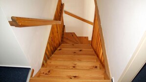 Una escalera de madera con un diseño sencillo y paredes blancas.