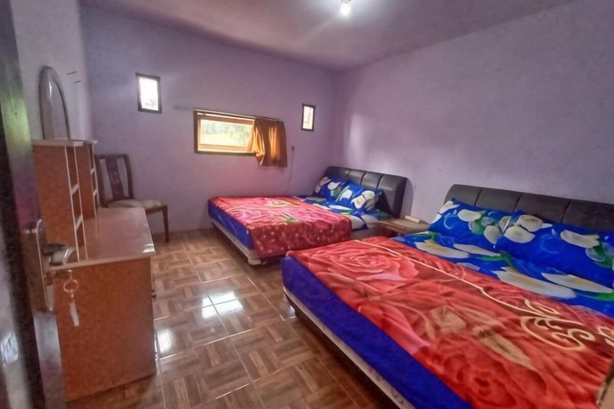 A room with two beds, a desk, and a window.