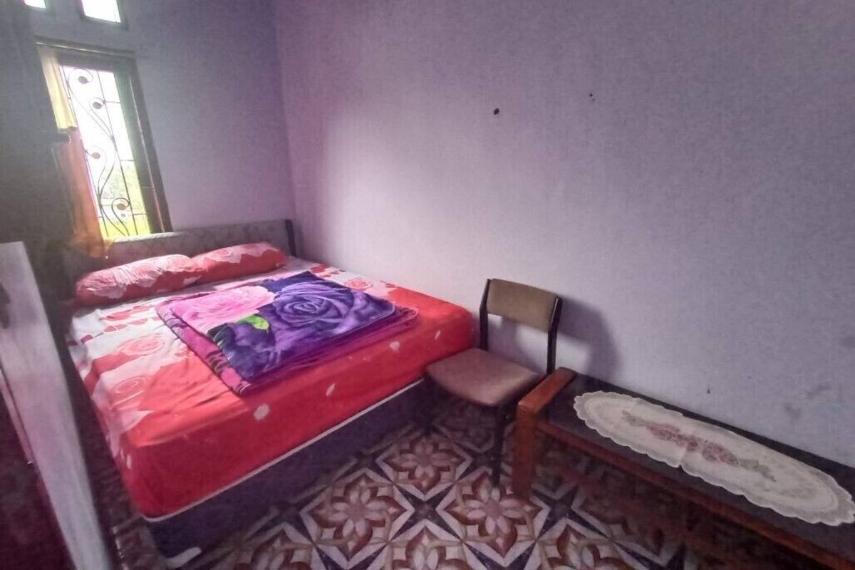 A bedroom with a bed, a chair, a small table, and a patterned floor.