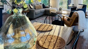 Ein geräumiges Wohnzimmer mit hoher Decke, großen Fenstern und einer gemütlichen Sitzecke.