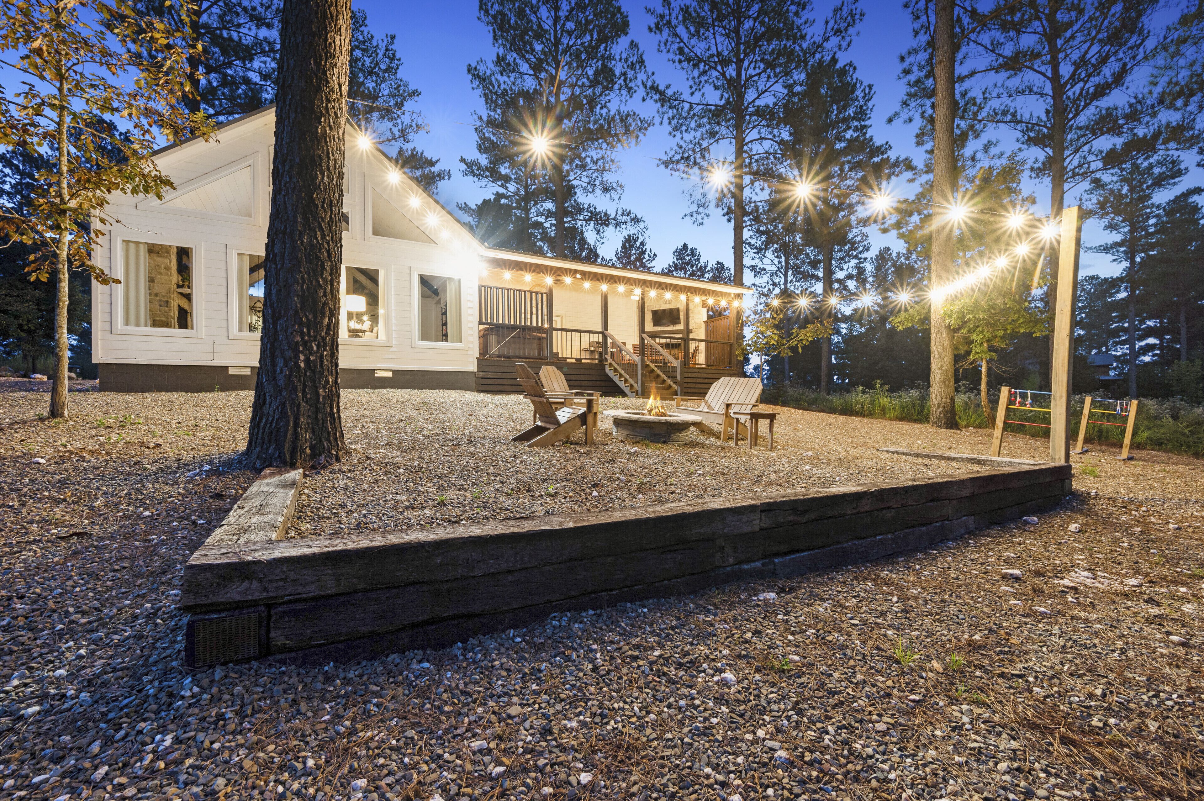 Una casa con porche cubierto, mobiliario exterior y luces colgantes.