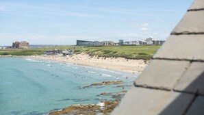 A coastal view with a beach, ocean, and buildings in the background. - The Penthouse Fistral Beach -  an apartment overlooking Fistral Beach sleeping six (Newquay)