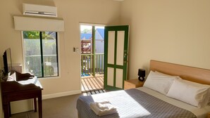 Un dormitorio con cama, mesita de noche y ventana.
