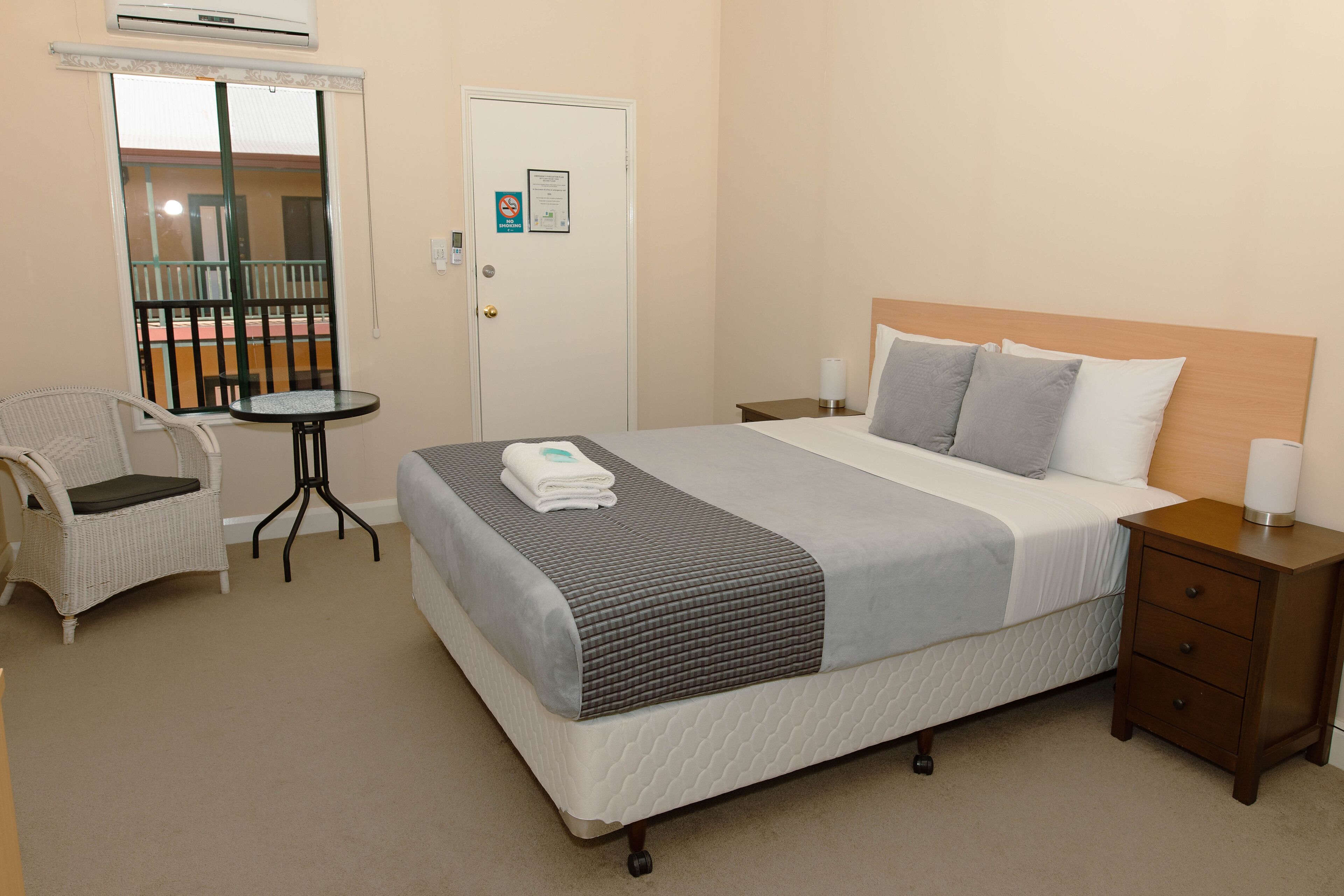 A hotel room with a bed, a chair, a small table, and a nightstand.