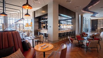 A modern restaurant with leather seating, round tables, and pendant lighting.