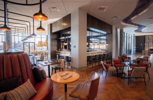 A modern restaurant with leather seating, round tables, and pendant lighting.