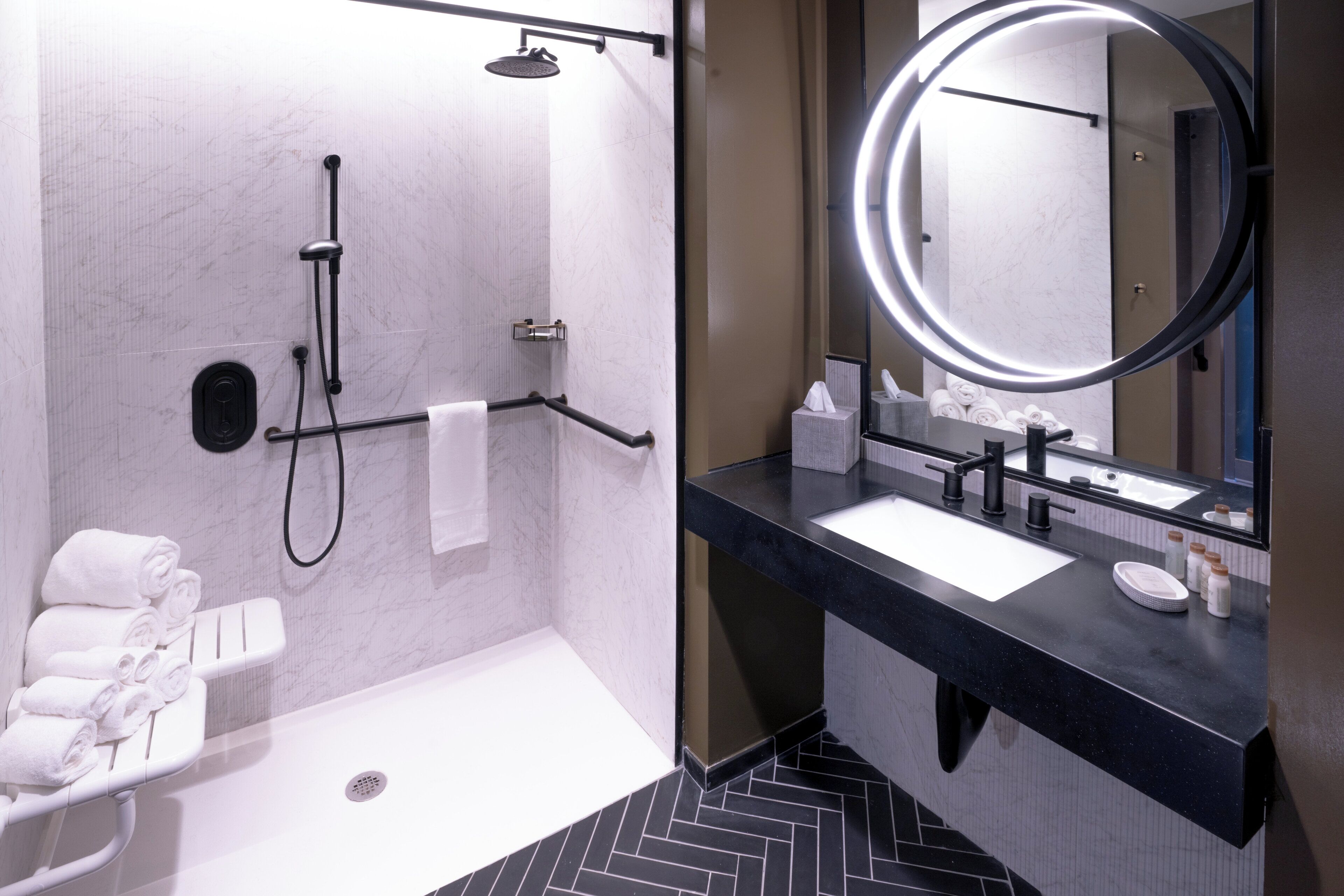 A modern bathroom with a walk-in shower, a vanity with a mirror, and a towel rack.