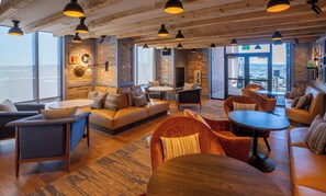 A spacious lounge area with leather sofas, round tables, and pendant lighting. - Hotel Indigo Columbus at Riverfront Place by IHG (Columbus)