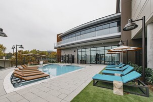 En modern byggnad med en swimmingpool, solstolar och parasoller.