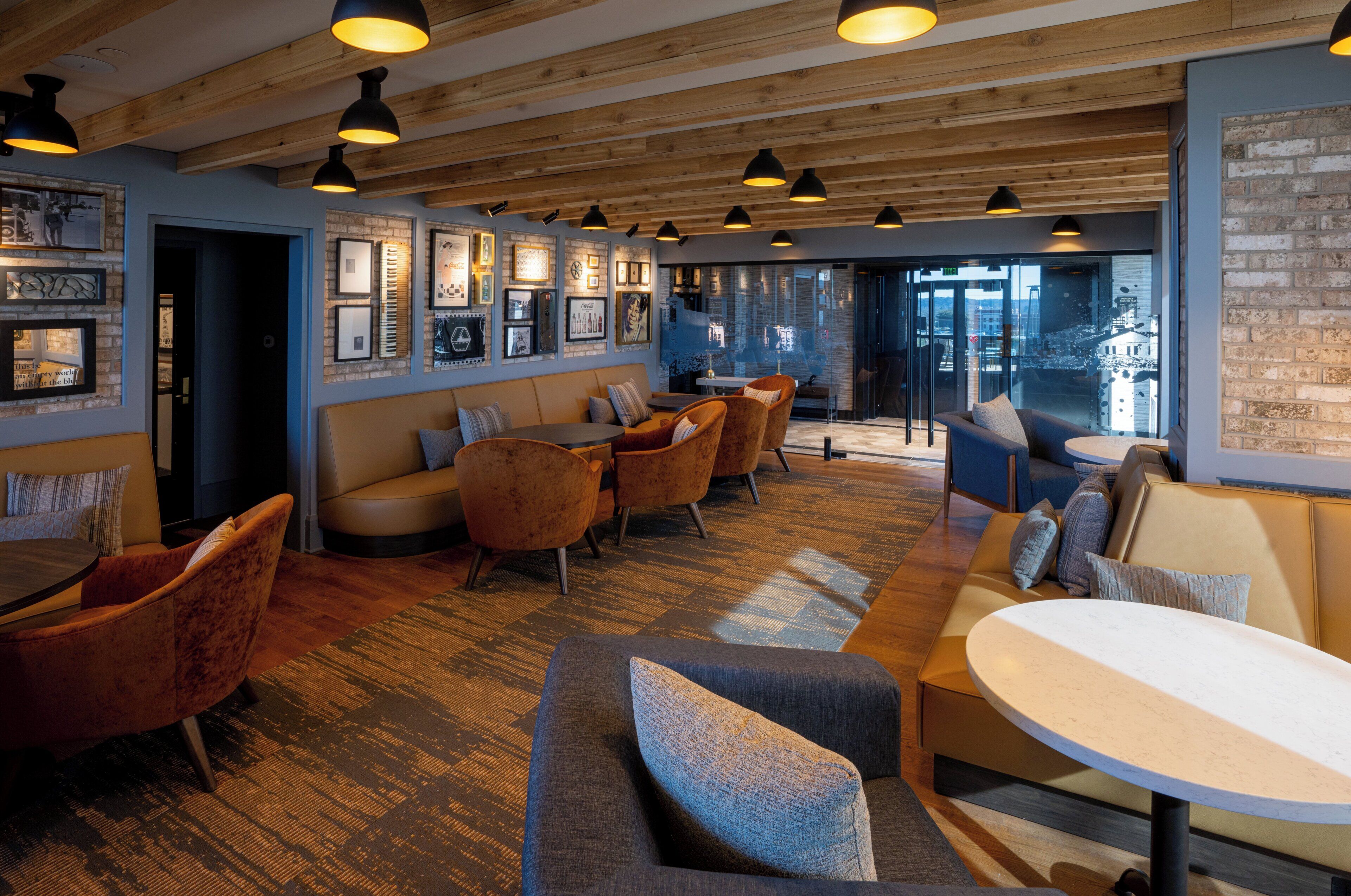 A modern interior with wooden beams, a seating area with sofas and chairs, and a wall with framed pictures.