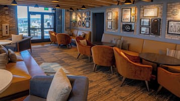 Un intérieur chaleureux avec des coins salon, une moquette à motifs et des tableaux encadrés accrochés aux murs.