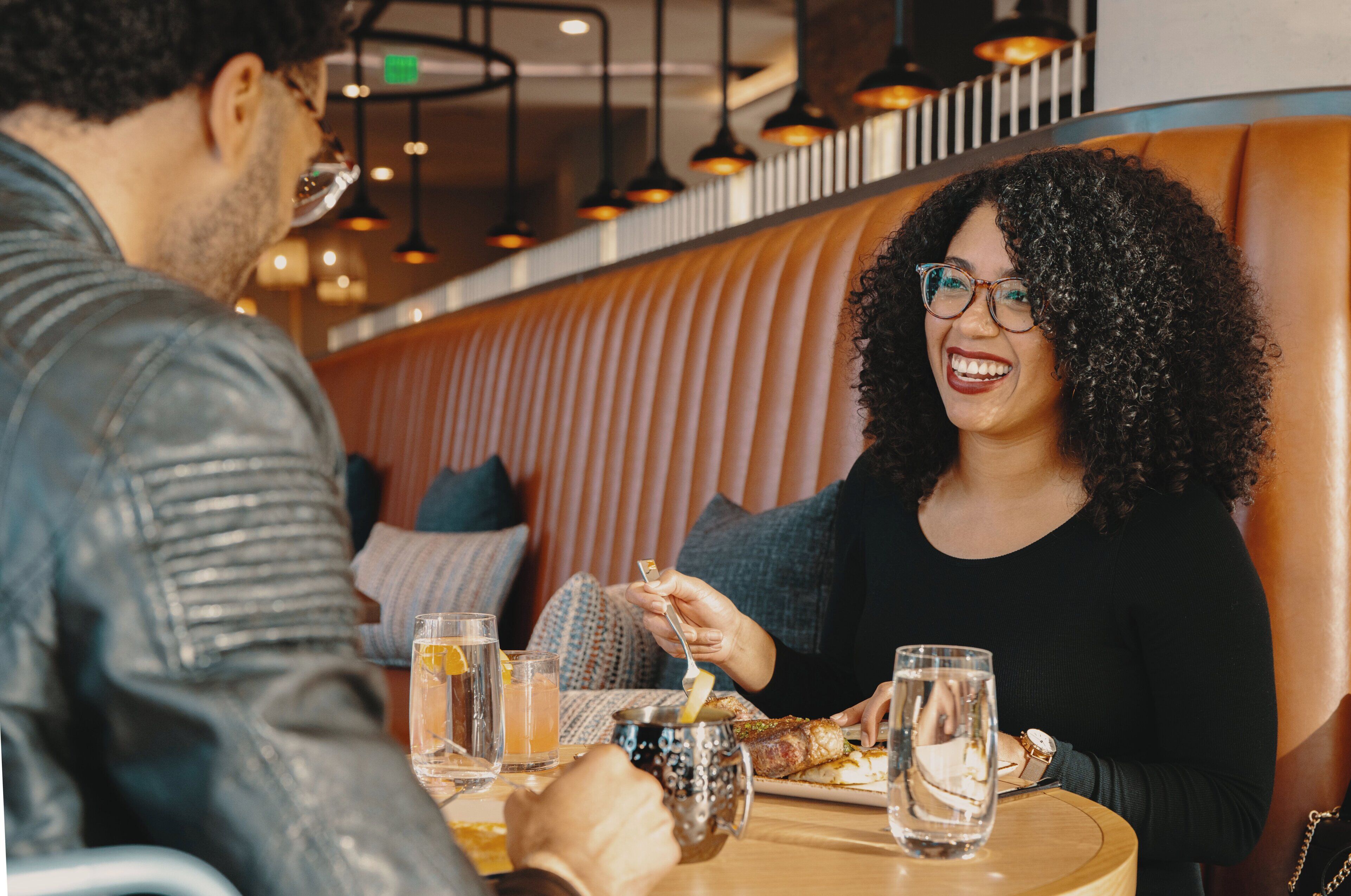A couple dining at a restaurant with a booth seating arrangement.