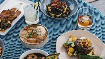 Una mesa con diversos platos que incluyen carne a la parrilla, arroz y verduras, acompañados de bebidas.