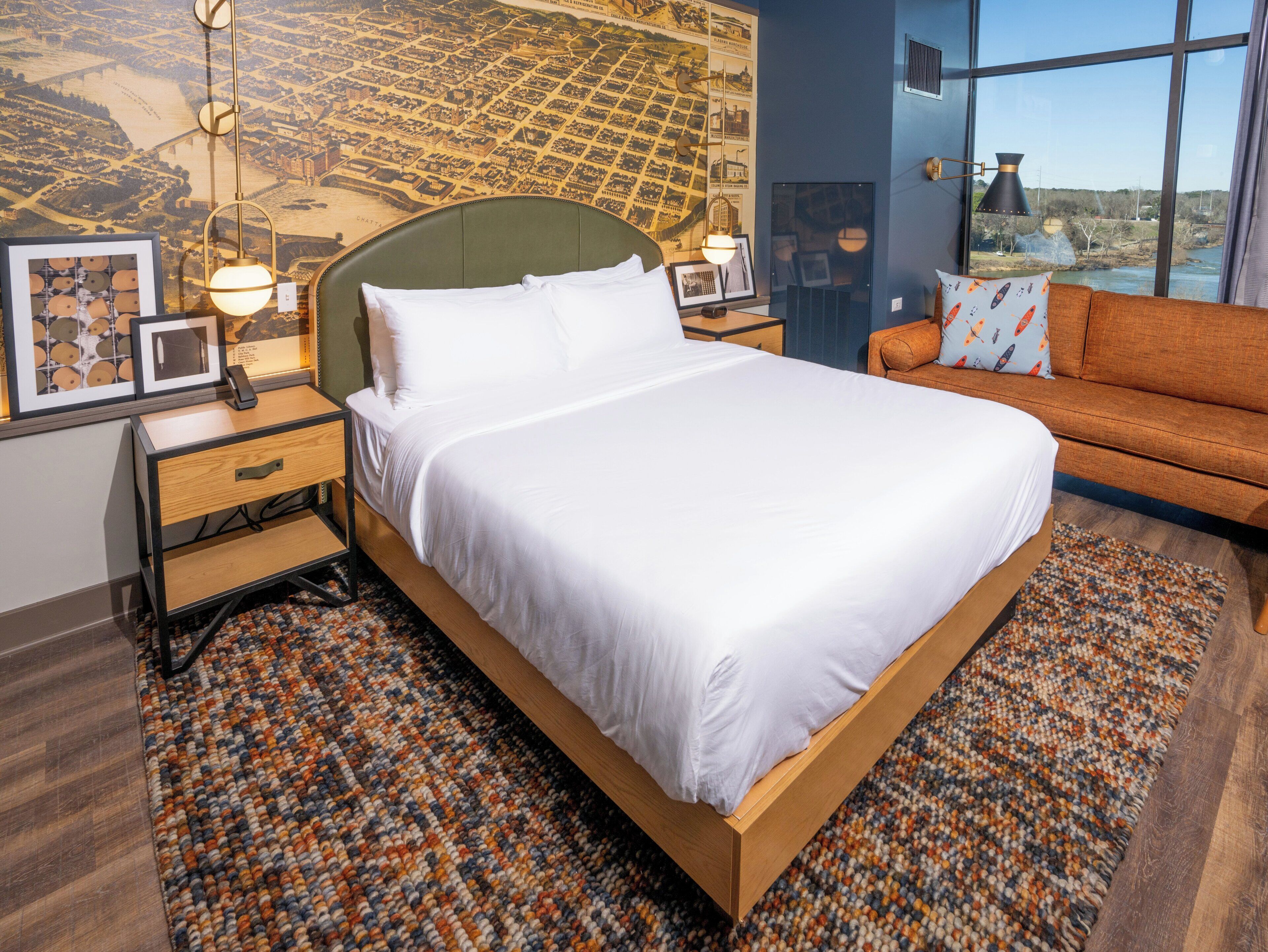Ein Hotelzimmer mit einem großen Bett, einem Schlafsofa, einem Nachttisch, einer Lampe und einer Wandkarte.
