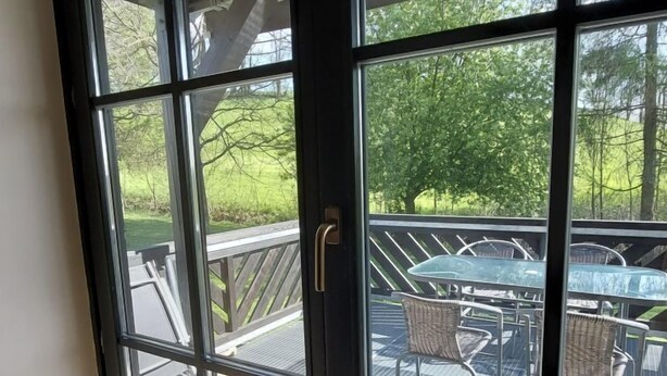 Una porta in vetro che dà su un patio esterno con tavolo e sedie.
