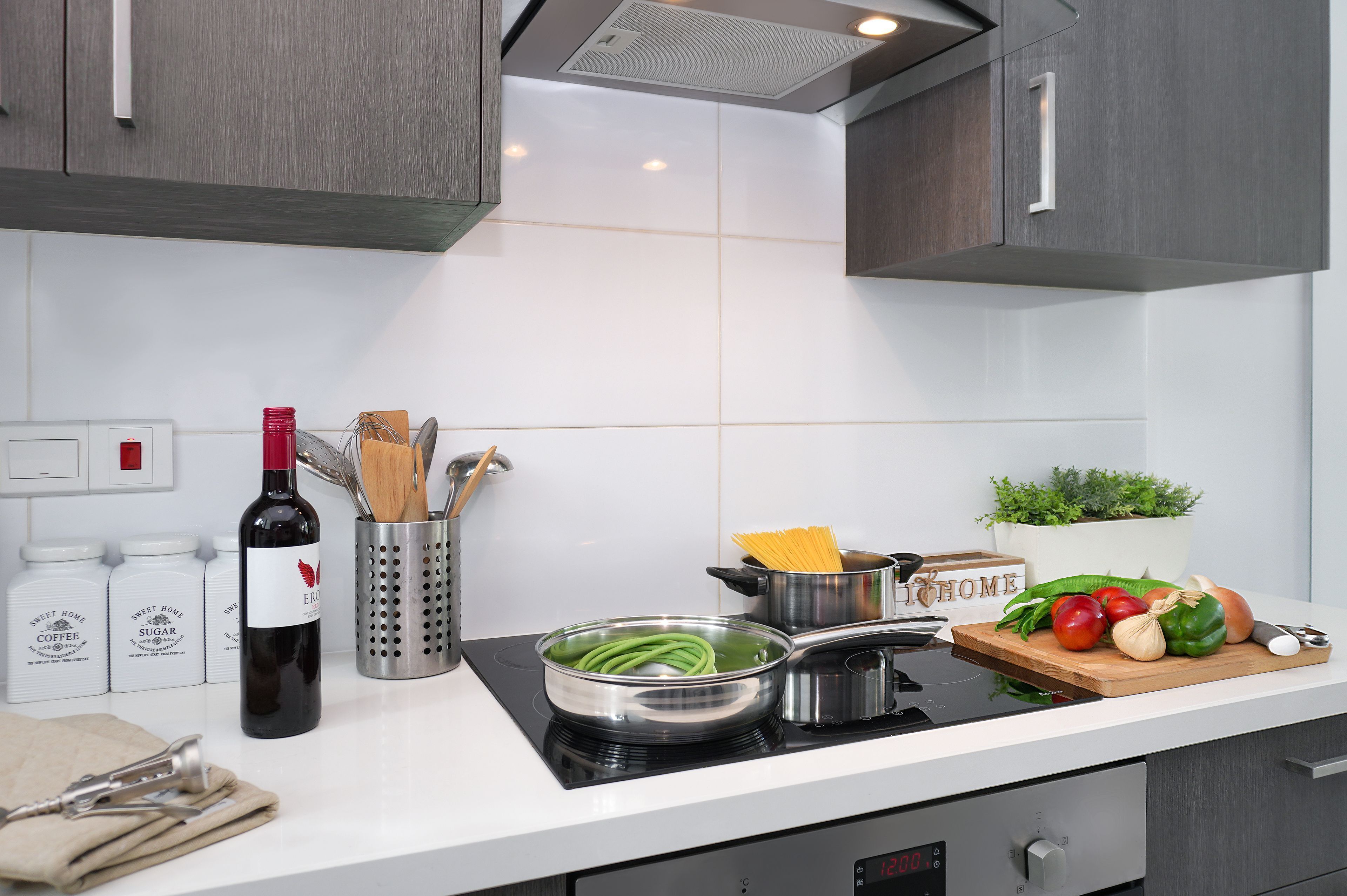 Una cocina moderna con encimera blanca, electrodomésticos de acero inoxidable y una variedad de productos frescos y utensilios de cocina.