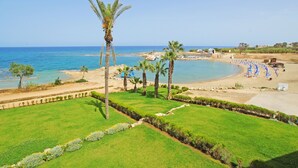 A coastal landscape with a beach, palm trees, and a clear sky. - VILLA APOLLONIA - Brand new villa walking to Trinity Beach (Paralimni)