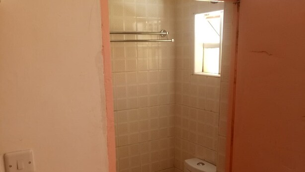 A small, narrow bathroom with a toilet and a shower area. - Silent Lodge (Mai Mahiu)