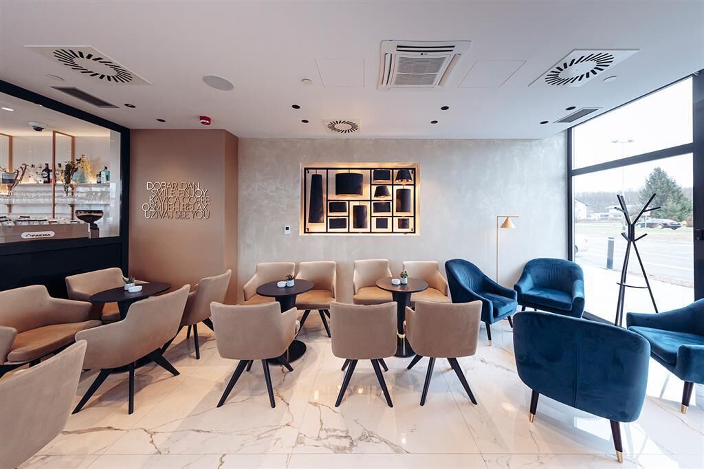 Un interior moderno con una zona de bar, asientos con mesas y un ventanal que ofrece vistas al exterior.