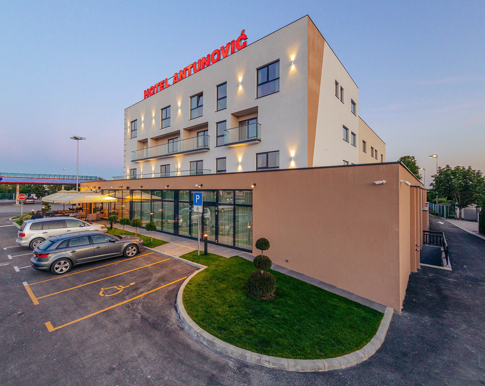 Un hotel moderno con fachada plana, varios pisos y un estacionamiento con espacios delimitados.