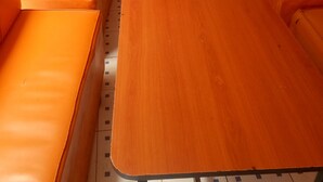 A seating area with orange leather booths and a wooden table. - Bidii Bar & Restaurant (Mai Mahiu)