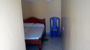 A narrow hallway with a bed, a blue plastic chair, and a blue plastic basket on the floor. - Bidii Bar & Restaurant (Mai Mahiu)