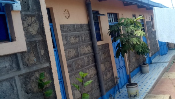 A building with a blue door, a window, and a potted plant. - Bidii Bar & Restaurant (Mai Mahiu)