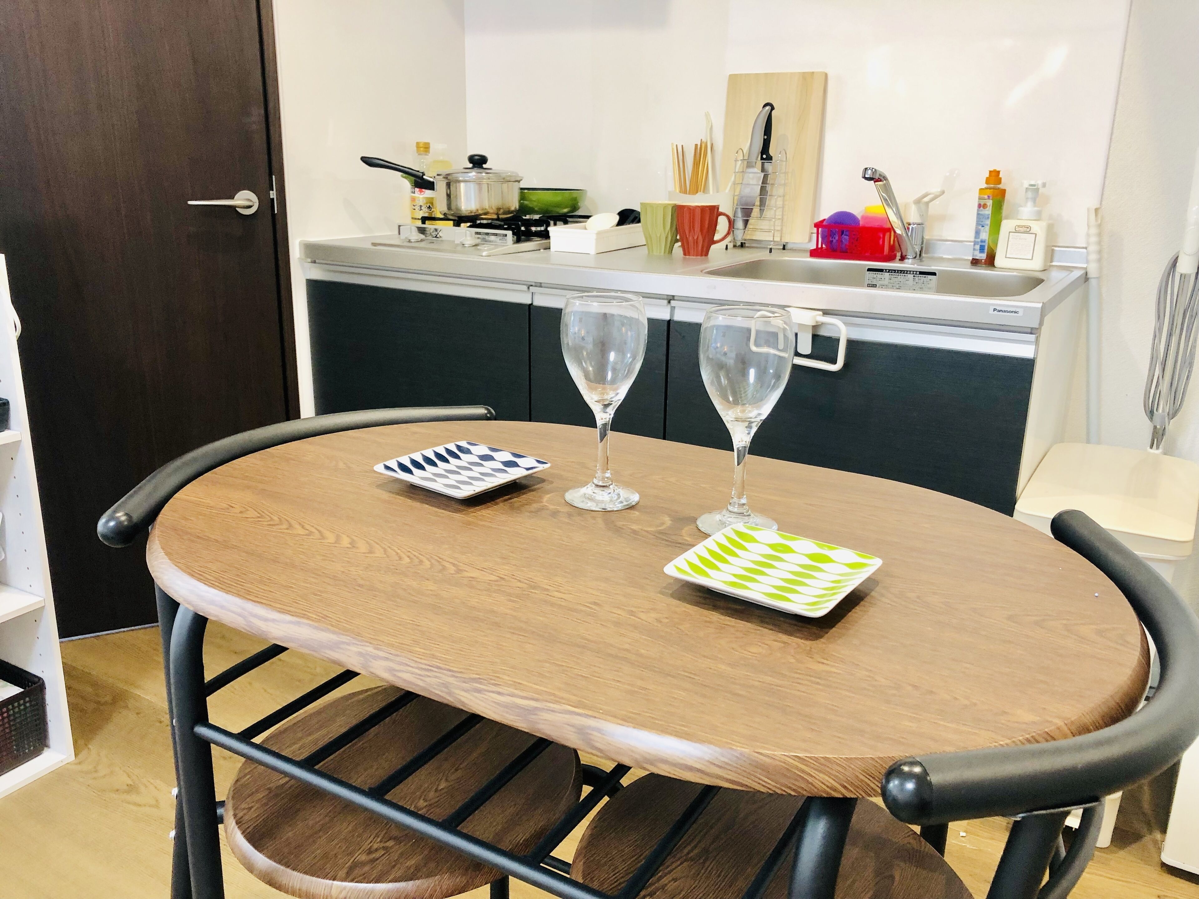A dining area with a round table, two wine glasses, and a plate.