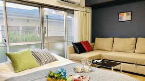 A hotel room with a bed, a sofa, a coffee table, and a window with curtains.