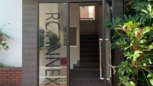 A modern building entrance with a glass door and a staircase leading inside.