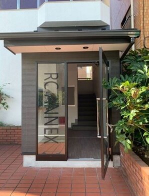 A modern building entrance with a glass door and a staircase leading inside.