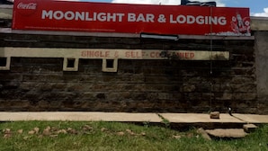 A building with a red banner advertising 'Moonlight Bar & Lodging' and a Coca-Cola logo. - Moonlight Bar & Lodging (Nakuru)