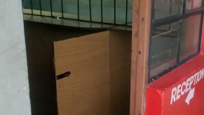 A reception area with a red wall, a glass door, and a wooden cabinet. - Tausi Bar & Lodging (Nakuru)
