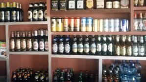 A liquor store with shelves stocked with various bottles and cans of alcohol. - Tausi Bar & Lodging (Nakuru)