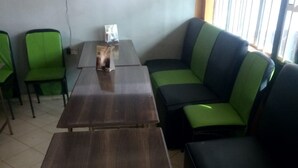A seating area with a dark wooden table and green upholstered chairs. - Tausi Bar & Lodging (Nakuru)
