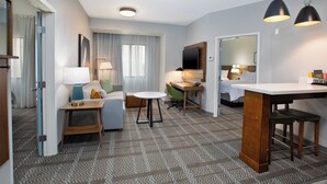 A hotel room with a sofa, a small table, a desk, and a TV. - Staybridge Suites Ames by IHG (Ames)