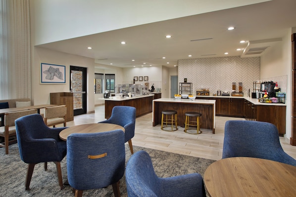 A modern hotel lobby with a bar area, seating arrangements, and a herringbone-patterned wall. - Staybridge Suites Ames by IHG (Ames)