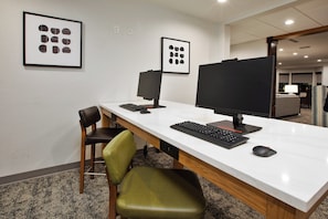 A modern office space with a white desk, two monitors, a keyboard, a mouse, and a green chair. - Staybridge Suites Ames by IHG (Ames)
