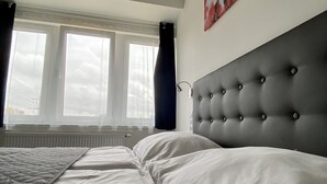 A bedroom with a large bed, a window with curtains, and a headboard. - HOTEL CHODOV ASC (Prague)