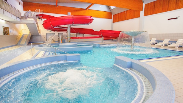 An indoor swimming pool with multiple slides and a hot tub area. - HOTEL CHODOV ASC (Prague)