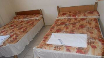 A room with two single beds, each with a floral-patterned bedspread and white sheets.