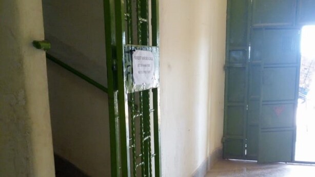 A hallway with a green metal gate, a staircase, and a tiled floor. - Mukuruwe-Ini Guest House (Marua)