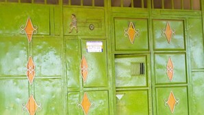 A green metal gate with decorative diamond patterns and a small sign. - Mukuruwe-Ini Guest House (Marua)