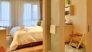 A hotel room with a bed, a desk, a chair, a small table, a mirror, a plant, and a bathroom with a shower and a toilet. - Shundi SHY Hotel West Lake Hangzhou (Hangzhou)