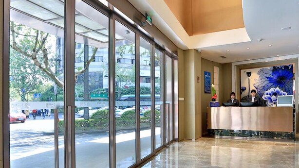 A hotel reception area with a glass facade, a reception desk, and a large blue floral mural on the wall. - Shundi SHY Hotel West Lake Hangzhou (Hangzhou)